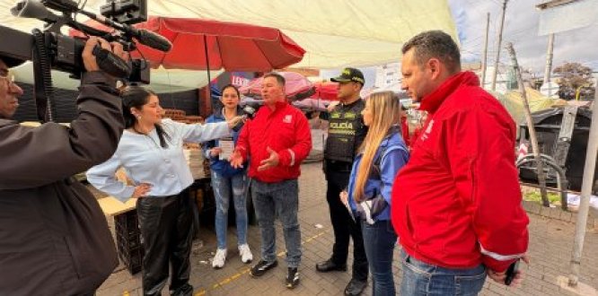 Funcionario de la Alcaldía Local entrega declaraciones a medios durante una jornada institucional en espacio público, acompañado por la Policía y equipo de trabajo, en una zona comercial intervenida.